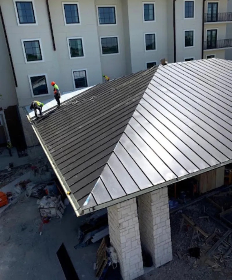 Crew installing standing seam metal roof panels on a commercial project in Midvale